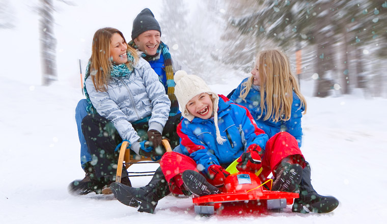 family enjoying snow sledding