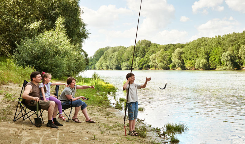 boy catching his first fish while fishing with family