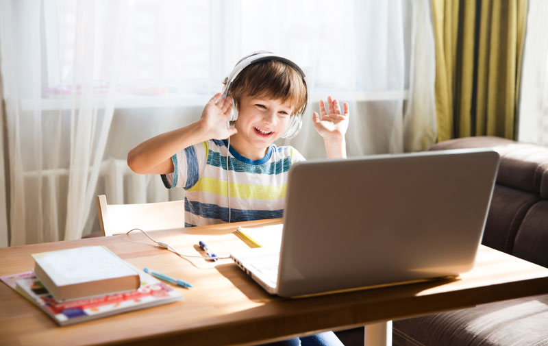 boy doing schoolworkfrom home on a laptop and smiling