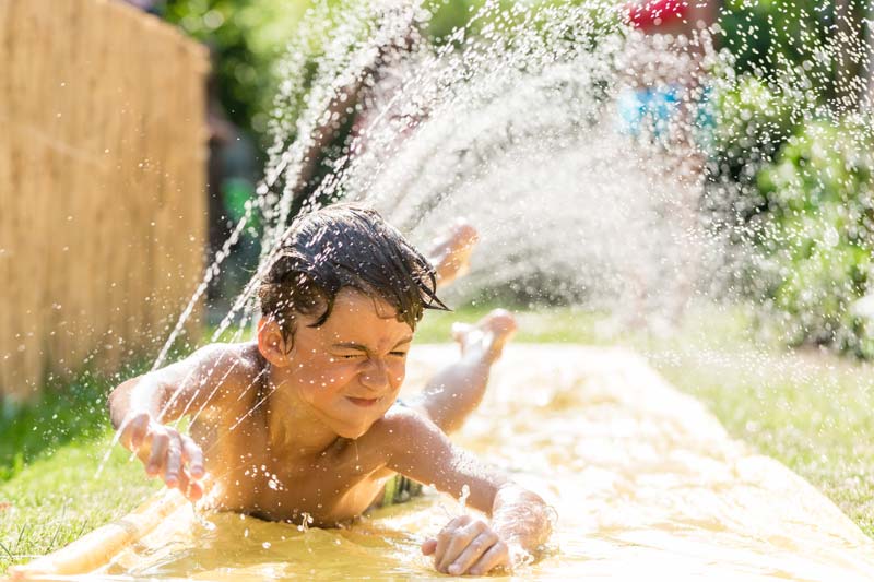 boy enjoying getting drenched on yard water slide