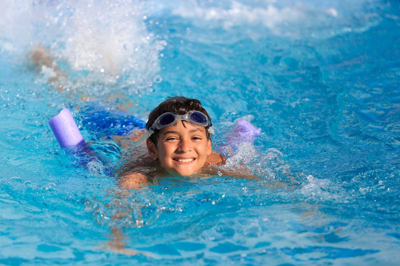 boy swimming with help of pool noodle