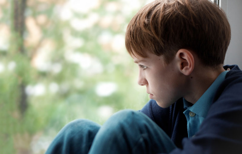 boy thinking and looking out of a window