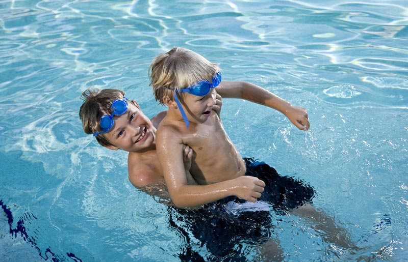 boys horseplaying in the swimming pool