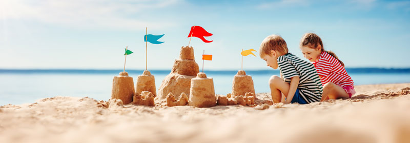 brother and sister at beach making sand castles