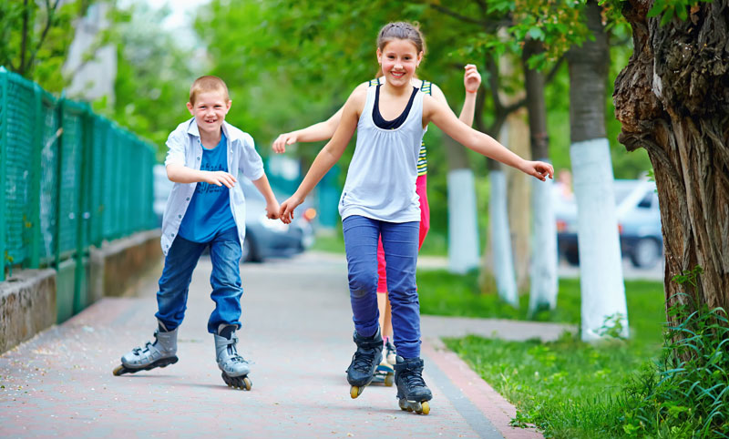 brother and sister rollerblading on the sidewalk