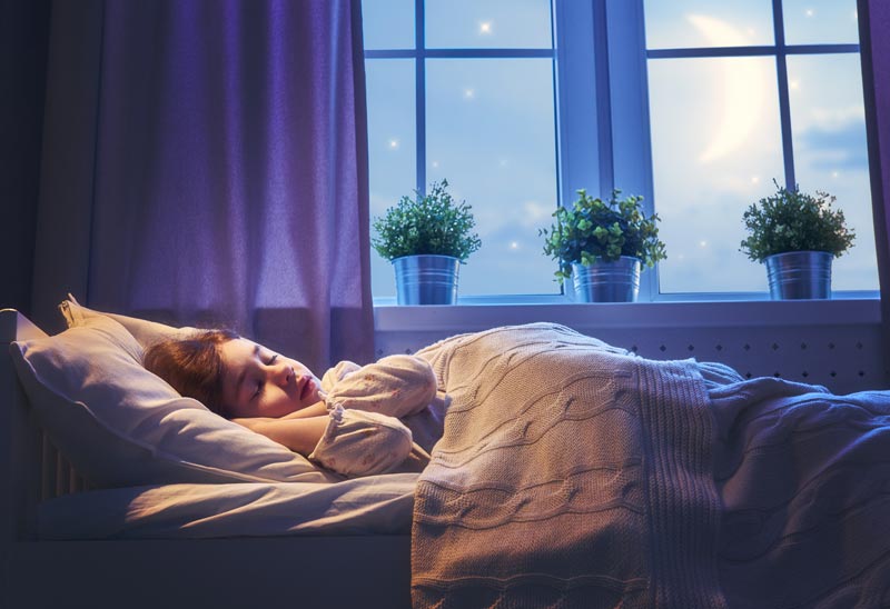 child happily and soundly sleeping while in bedroom