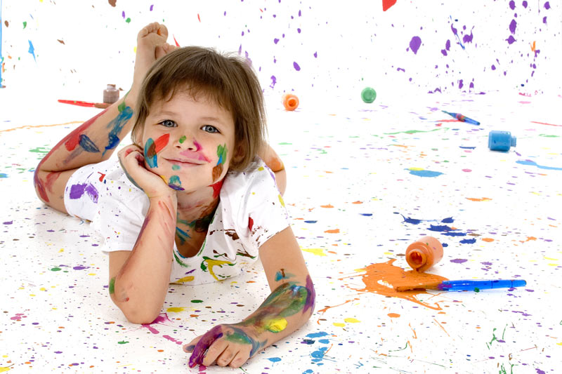 child with paint everywhere inculding on the walls on their clothes and on the floor