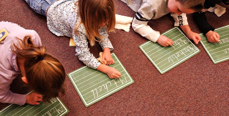 children on the floor working on their handwriting