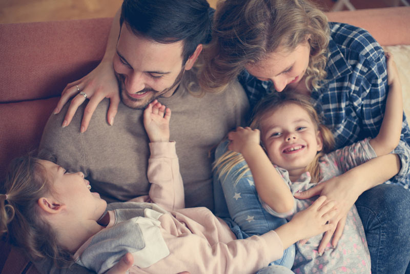 dad and mom tickling young kids