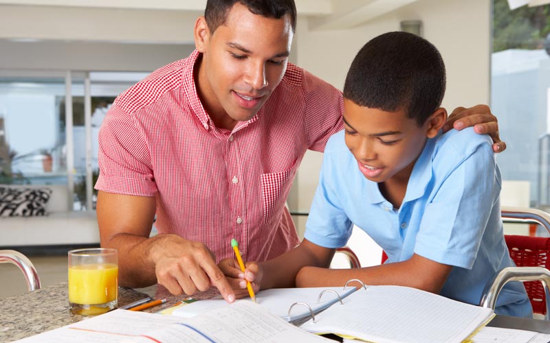 dad helping middle school aged son with homework in kitchen