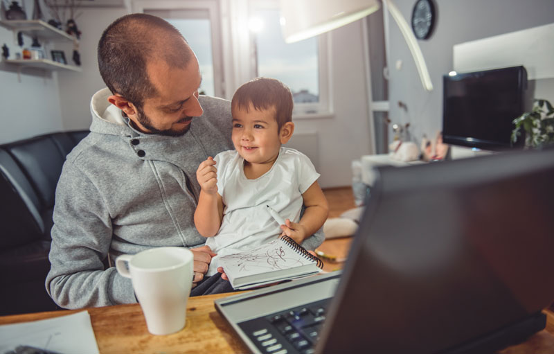dad working from home and tending to young child