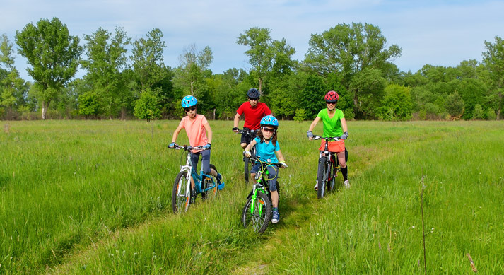 family biking through a grassy field