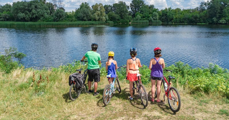 family on bikes beside river front