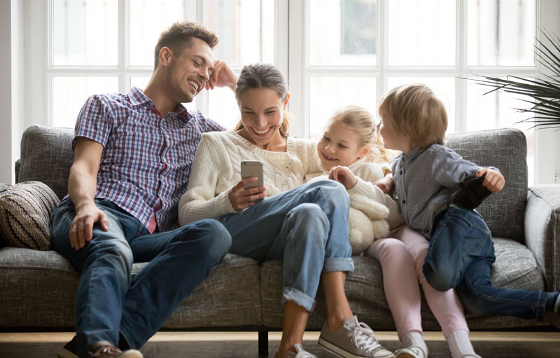 family on sofa looking at moms phone pictures