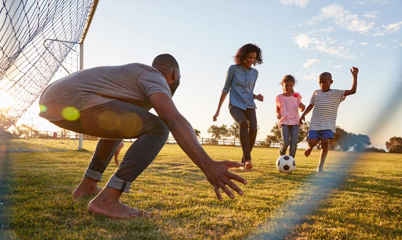 family playing soccer with dad as goalie