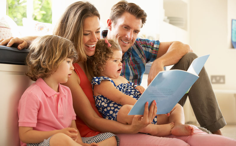 family with young children listening to a story from a book