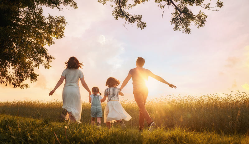family with young kids in a field as the sun is setting