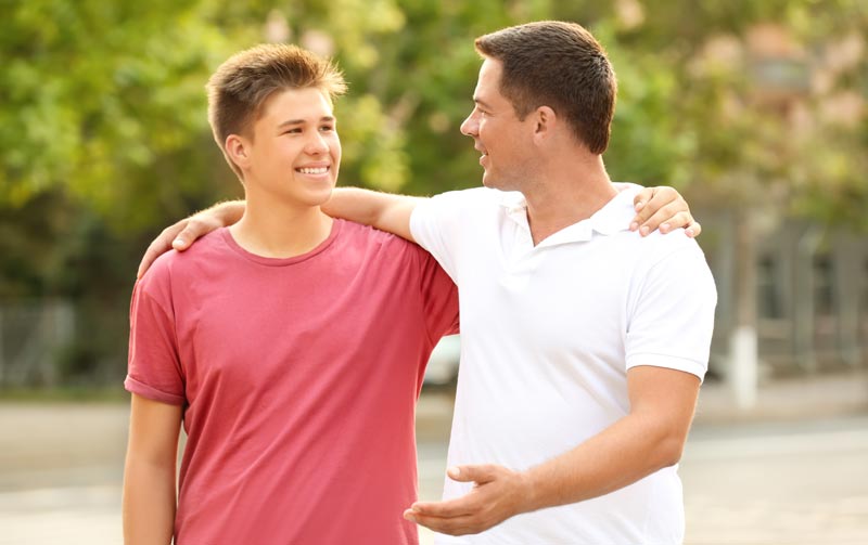 father and son outside happily talking while walking