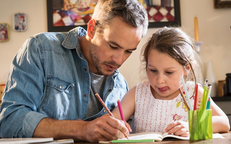 father helping elementary age daughter with homework