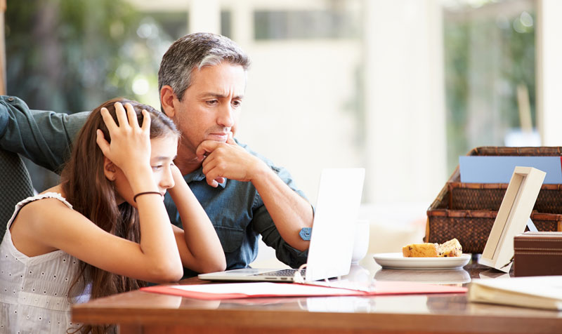 father helping overwhelmed daughter with her schoolwork