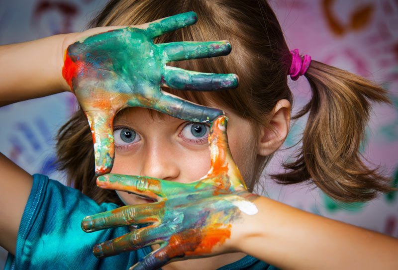 girl posing for picture with fingerpaint on her hands