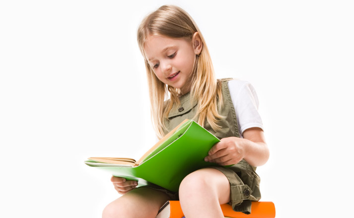 girl sitting on stack of books reading a book