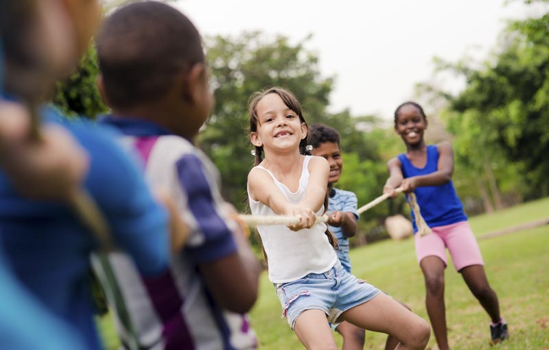 group of your kids playing tug of war outdoors