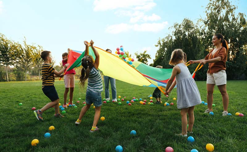 group of kids playing game with little plastic balls and parachute