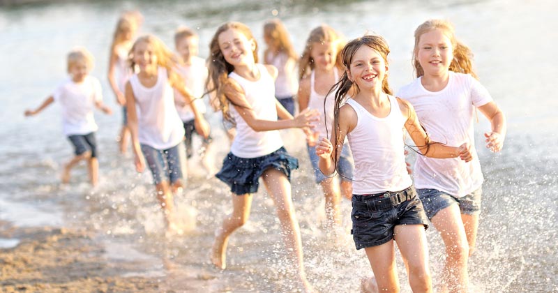 group of young girls running on the beach