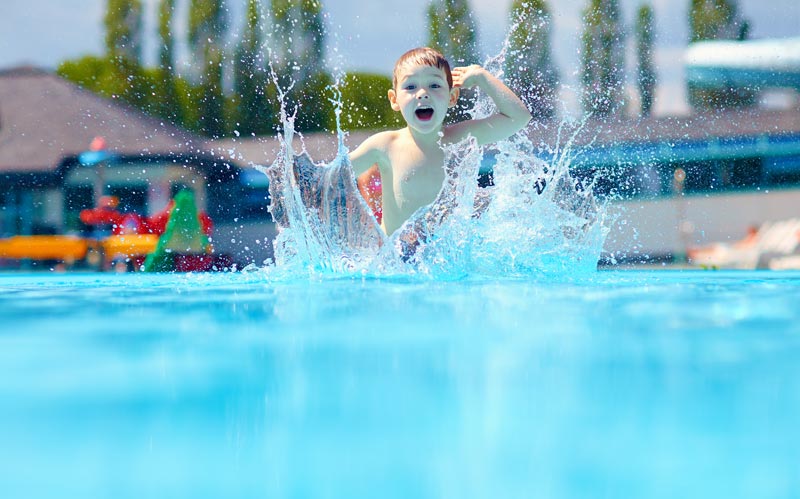 happy boy jumping into outdoor swimming pool