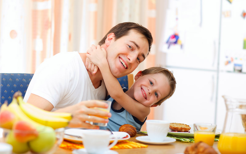 happy dad and young son eating breakfast