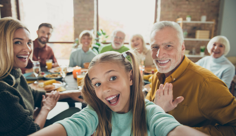 happy family at a meal showing online video of themselves with friends