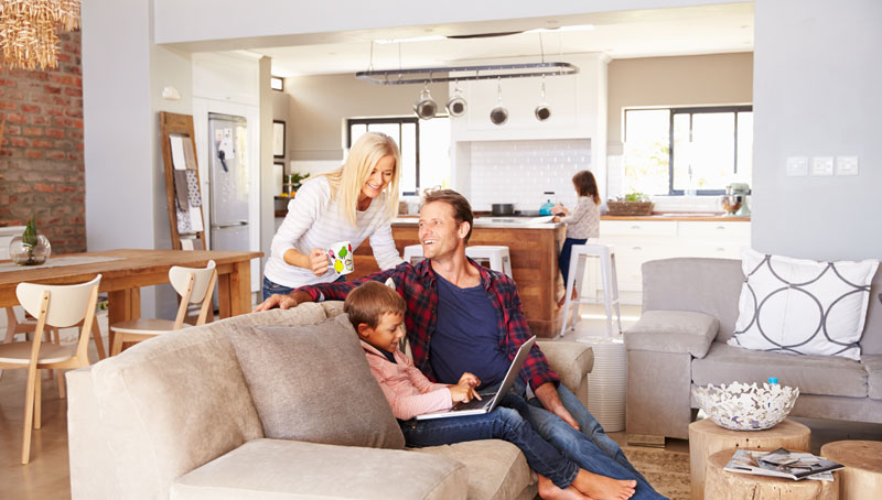 happy family in their home with young child working on a laptop
