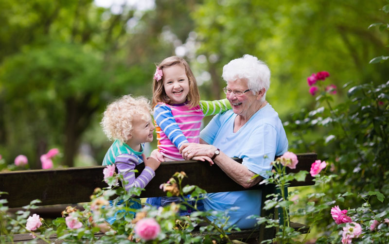 happy grandkids with grandmother in park with flowers