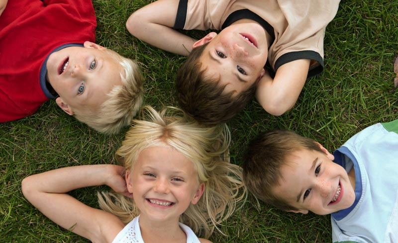 happy young friends lying on the green grass