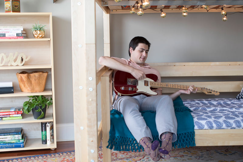 high school boy playing a guitar while sitting on a Maxtrix bed