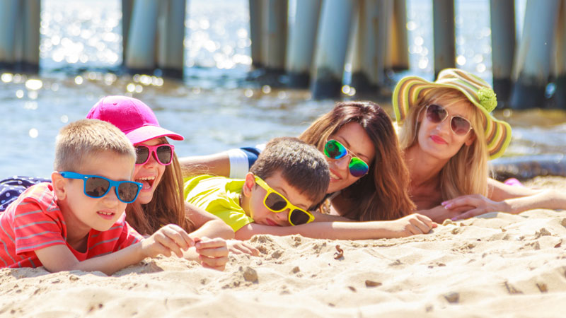 kids and moms lying on sandy beach