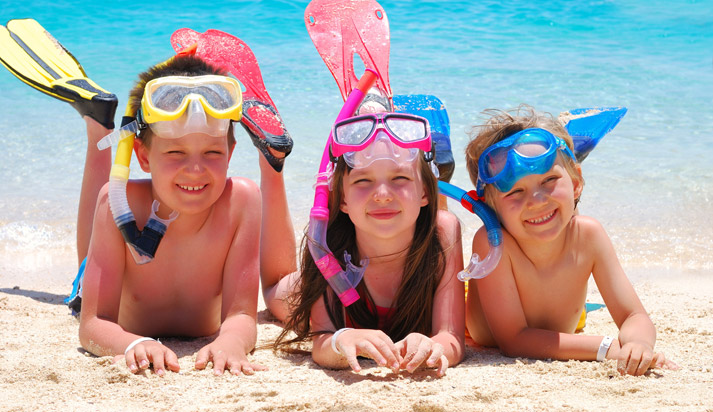 kids with swimming gear on lying on the sand happily