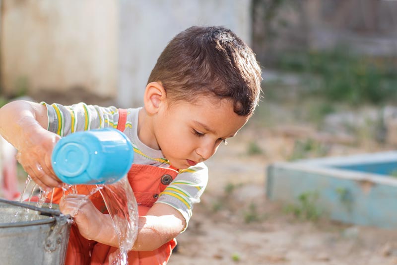 little boy playing with buckets of water