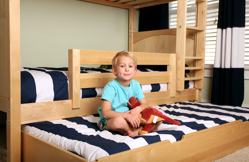 little boy sitting on Maxtrix trundle bed with dinosaur