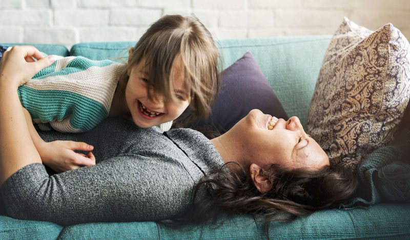 little girl and mom laughing on the sofa