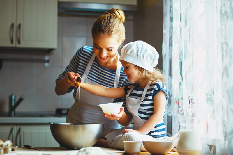 little girl helping mom with recipe making in the kitchen