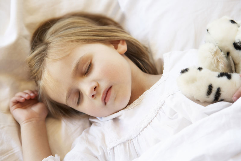 little girl sleeping in bed with stuffed animals
