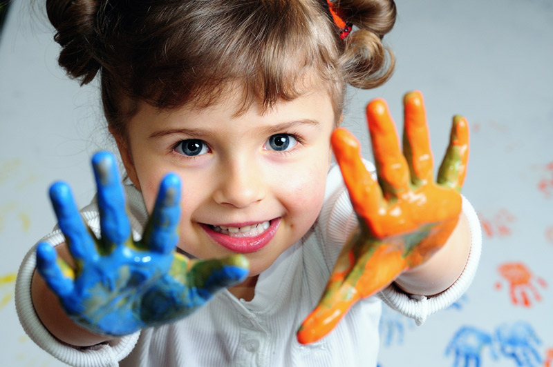 little girl with multi colored paint on both hands