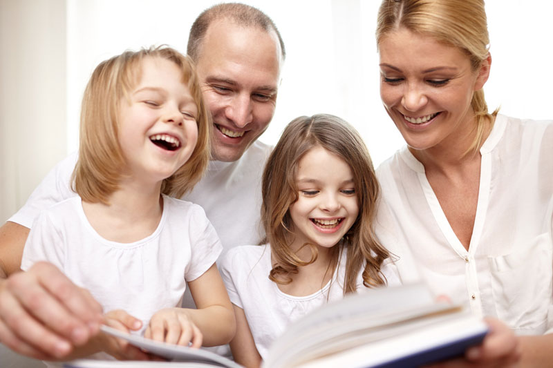 loving parents reading book to their two young children