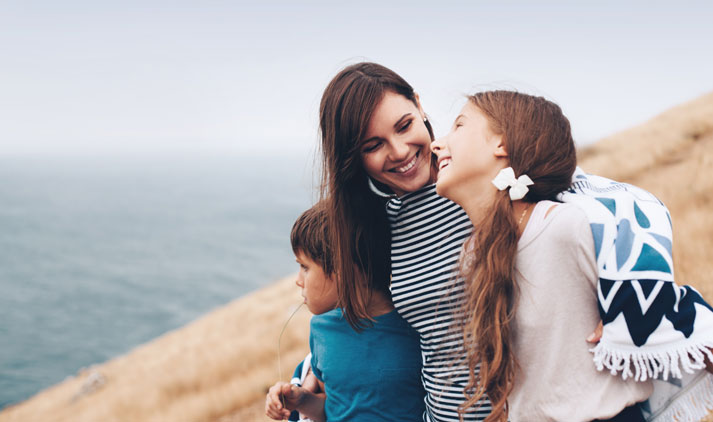 mom and two kids walking by the beach