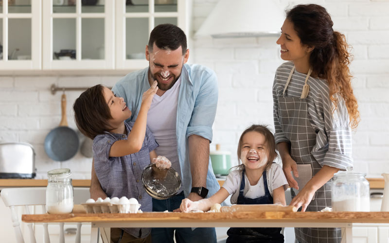 mom and dad and two young kids cooking up a storm in the kitchen