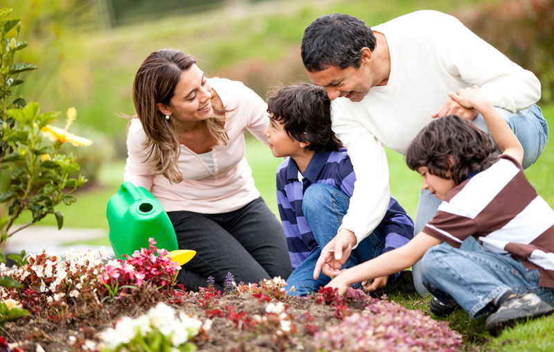 mom and dad outside with kids tending to gardening flowers