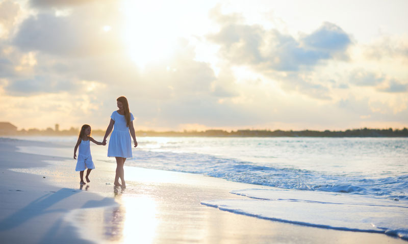 mother and daughter walking along the shore