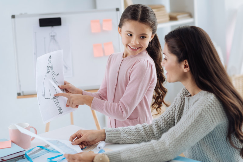 mother and young daughter looking at fashion drawings